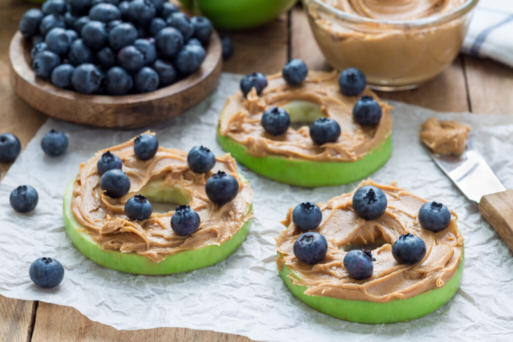 green apples sliced into wheels with peanut butter and blueberries