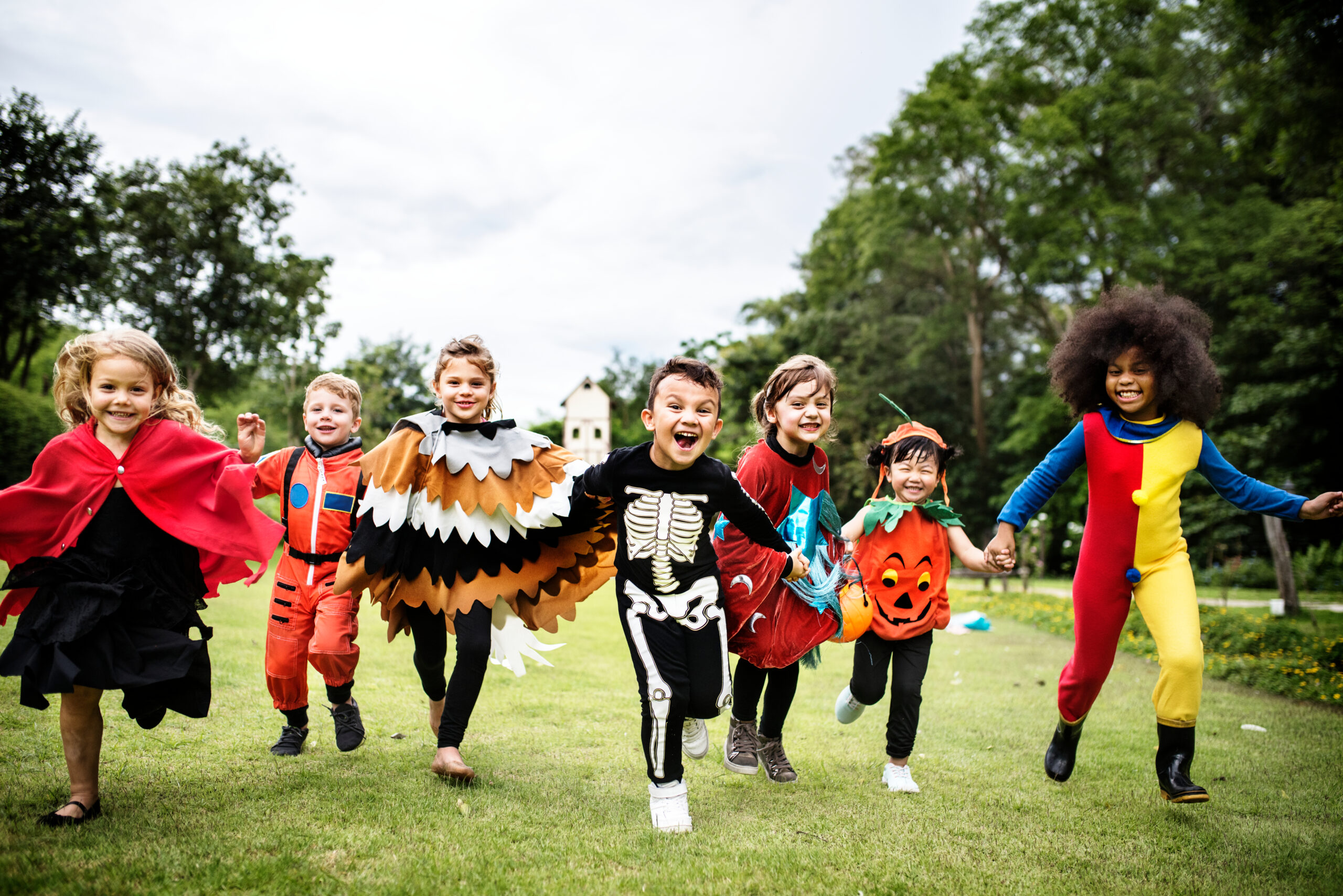 Children in various Halloween costumes happily running.